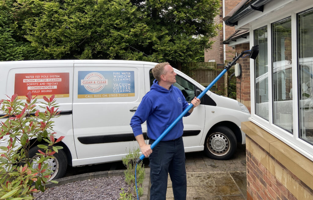 Professional window cleaner efficiently cleaning a large office window with an extendable brush